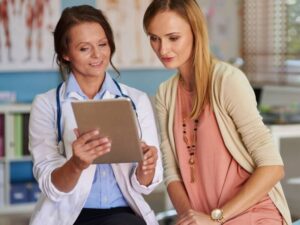 Médica analisando dados com paciente em tablet